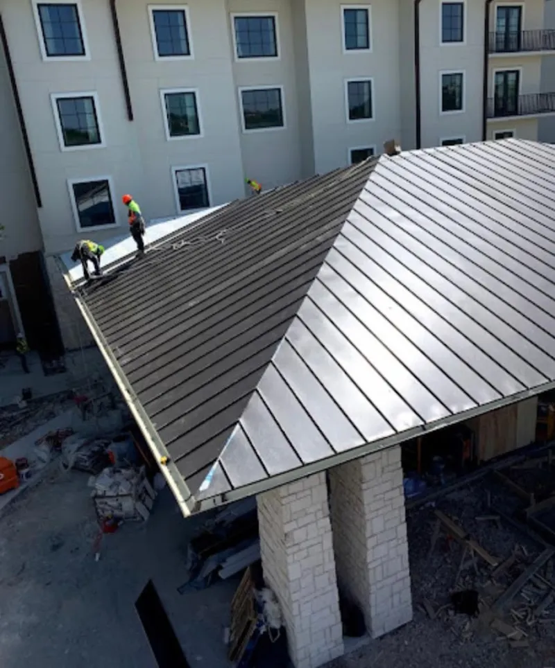 Crew installing standing seam metal roof panels on a commercial project in Millersville